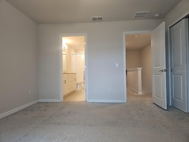 unfurnished bedroom featuring light colored carpet, connected bathroom, and a closet