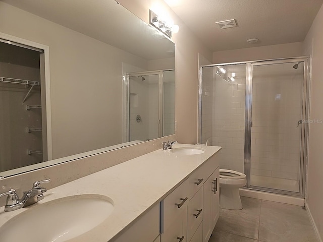 bathroom featuring vanity, toilet, tile patterned flooring, and a shower with door