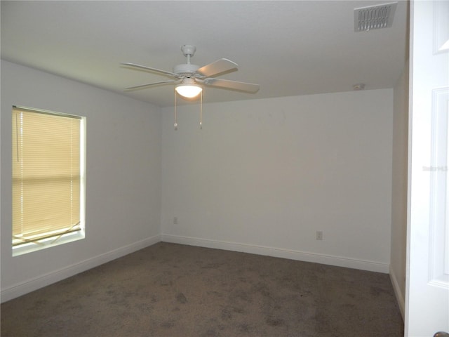 empty room featuring ceiling fan and dark colored carpet