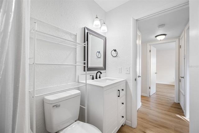 bathroom with hardwood / wood-style flooring, vanity, and toilet