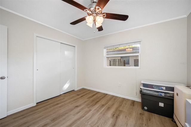 unfurnished bedroom featuring ceiling fan, ornamental molding, a closet, and light wood-type flooring