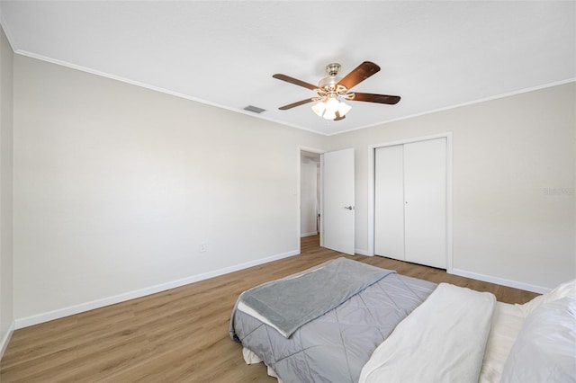 bedroom featuring hardwood / wood-style flooring, ornamental molding, ceiling fan, and a closet