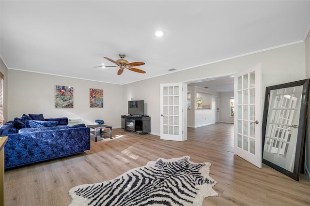 living room featuring ornamental molding, french doors, ceiling fan, and light wood-type flooring