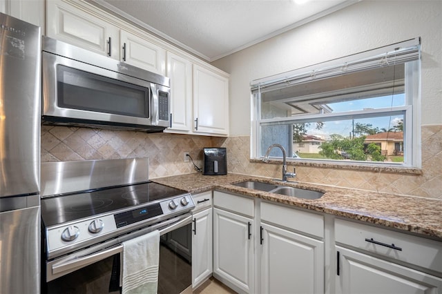 kitchen featuring stainless steel appliances, white cabinetry, sink, and backsplash