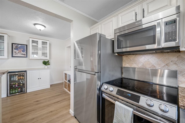 kitchen featuring crown molding, stainless steel appliances, wine cooler, white cabinets, and light wood-type flooring