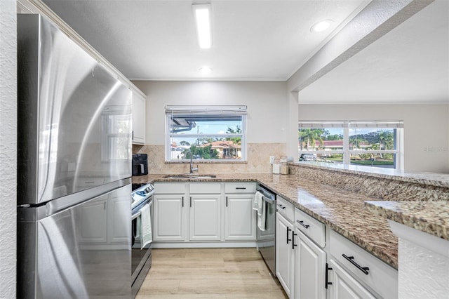 kitchen featuring tasteful backsplash, white cabinetry, sink, light stone counters, and stainless steel appliances