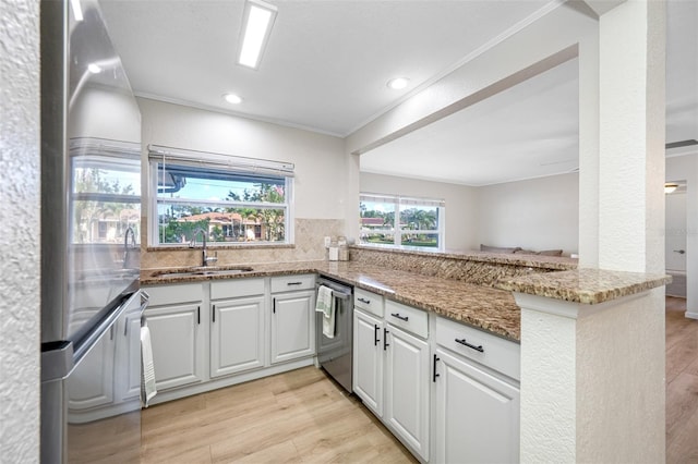 kitchen with stainless steel appliances, kitchen peninsula, sink, and white cabinets