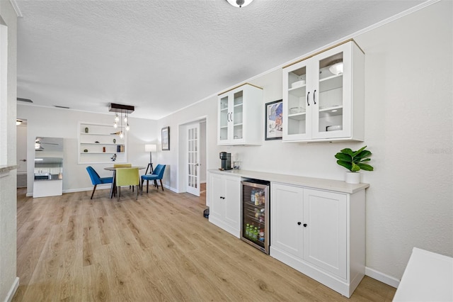 kitchen featuring white cabinets, pendant lighting, beverage cooler, and light hardwood / wood-style flooring