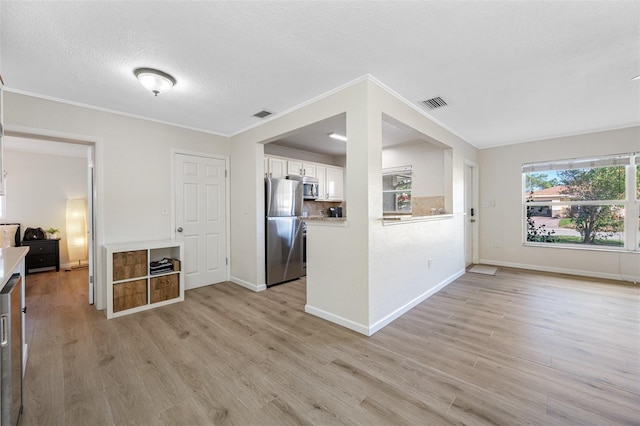 kitchen featuring white cabinetry, stainless steel appliances, light hardwood / wood-style floors, and a textured ceiling