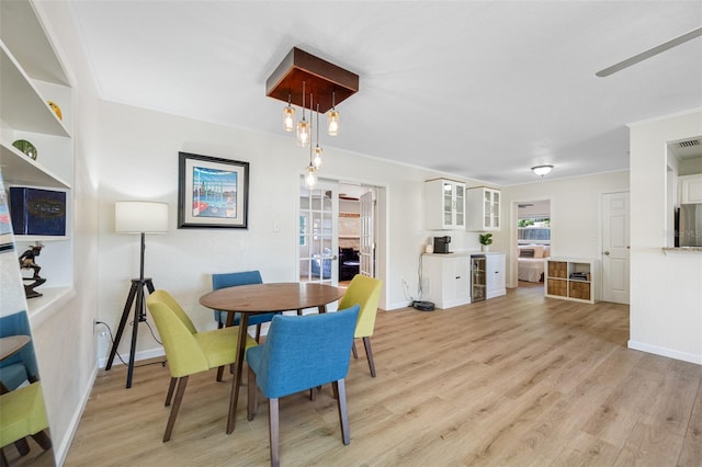 dining area with crown molding, light hardwood / wood-style flooring, and beverage cooler