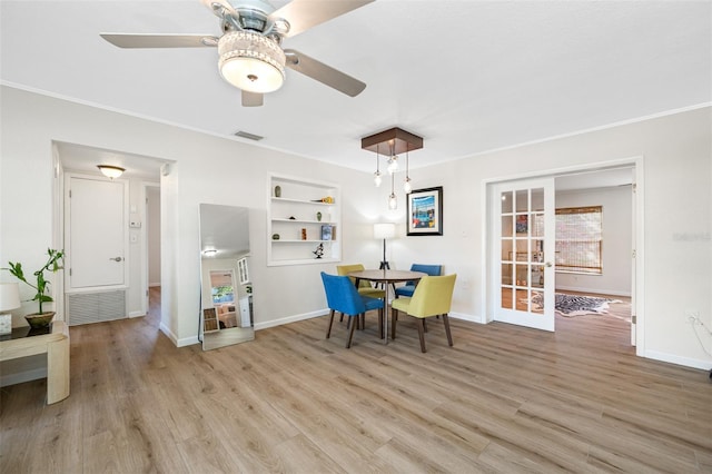 dining area featuring built in shelves, french doors, crown molding, ceiling fan, and light hardwood / wood-style floors