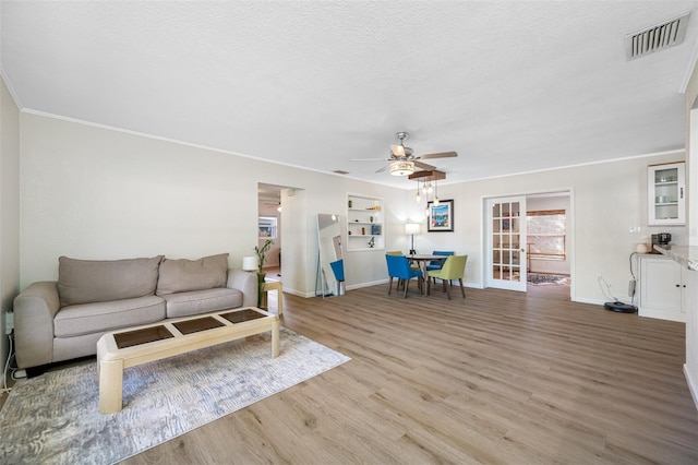 living room featuring crown molding, ceiling fan, light hardwood / wood-style floors, and a textured ceiling