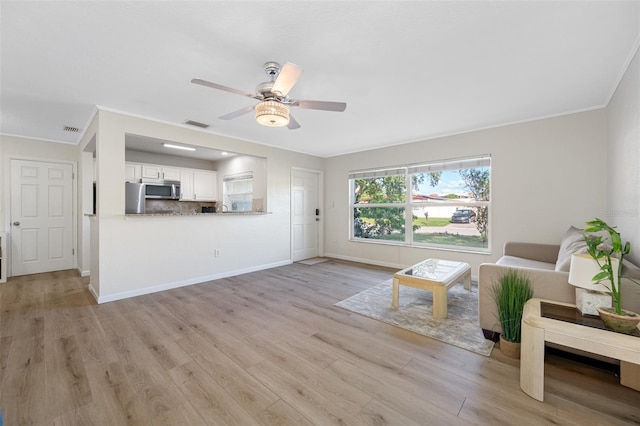 unfurnished living room featuring crown molding, ceiling fan, and light wood-type flooring