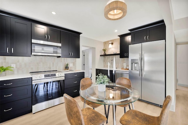 kitchen featuring tasteful backsplash, sink, stainless steel appliances, and light wood-type flooring