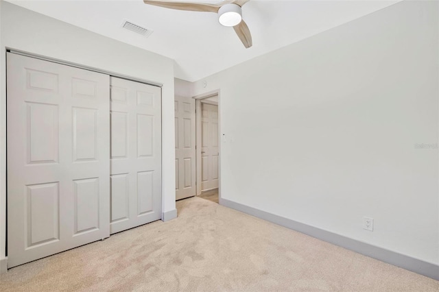 unfurnished bedroom with ceiling fan, light colored carpet, and a closet