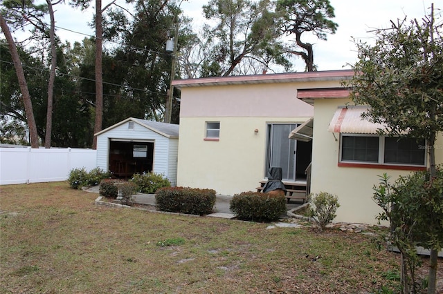 back of house featuring a garage, a lawn, and an outdoor structure