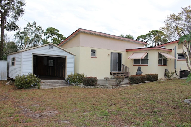 back of house with an outbuilding, a garage, central AC, and a lawn