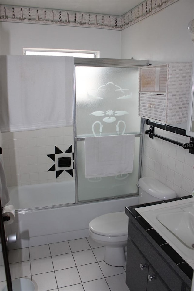 full bathroom featuring toilet, shower / bath combination with glass door, tile walls, vanity, and tile patterned flooring