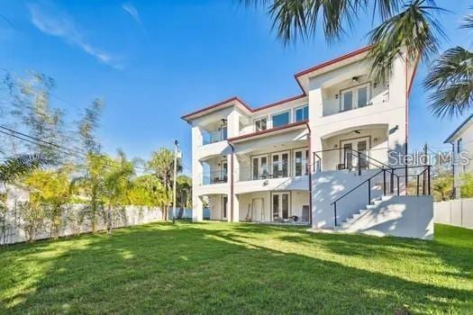 back of property with a yard and a balcony