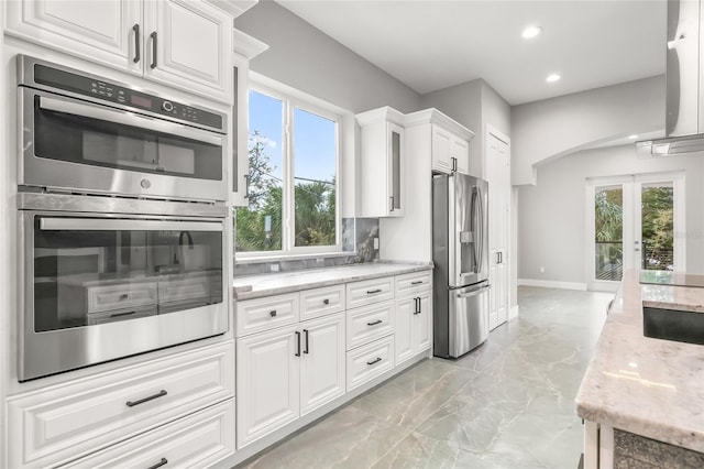 kitchen featuring stainless steel appliances, a wealth of natural light, marble finish floor, and white cabinets