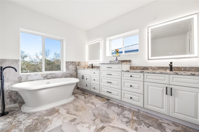 bathroom featuring vanity, a tub, and tile walls