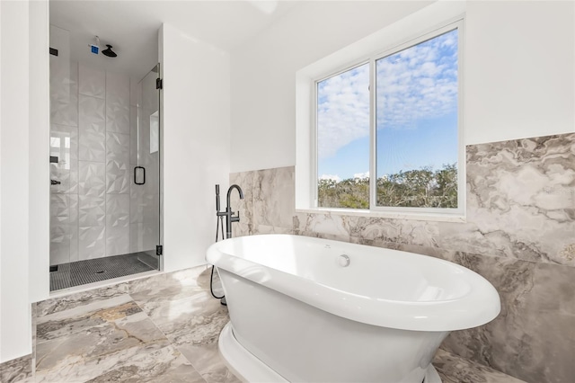 bathroom with marble finish floor, a stall shower, a soaking tub, and tile walls