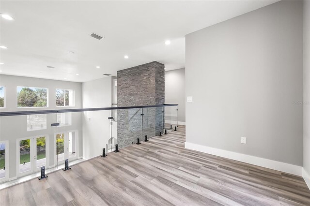 unfurnished room with recessed lighting, wood finished floors, a towering ceiling, visible vents, and baseboards