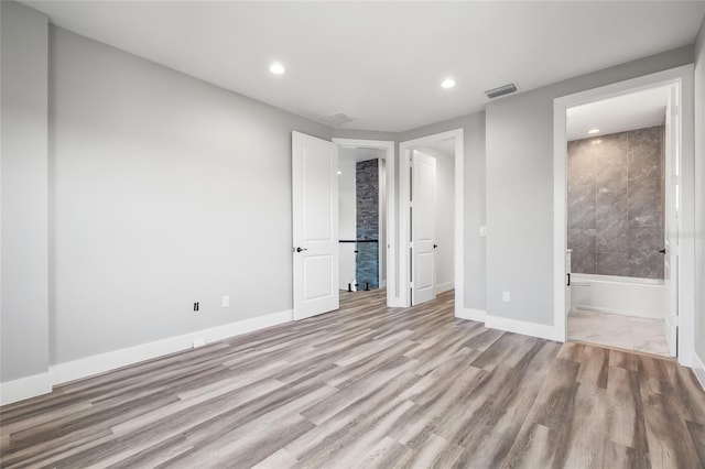 unfurnished bedroom featuring connected bathroom and light hardwood / wood-style flooring