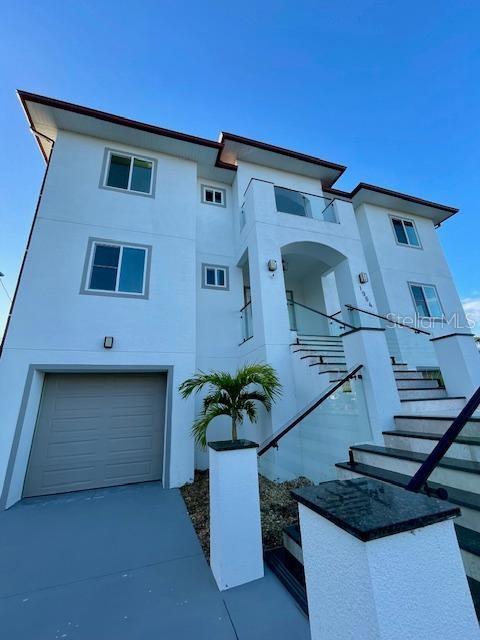 view of front of house featuring an attached garage, stairway, concrete driveway, and stucco siding