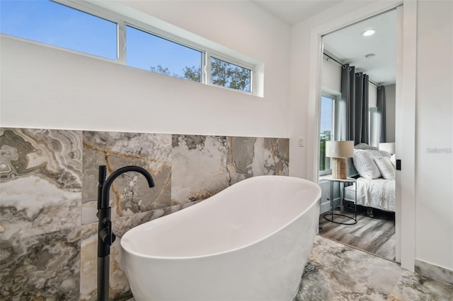 ensuite bathroom with a freestanding tub, tile walls, and ensuite bathroom