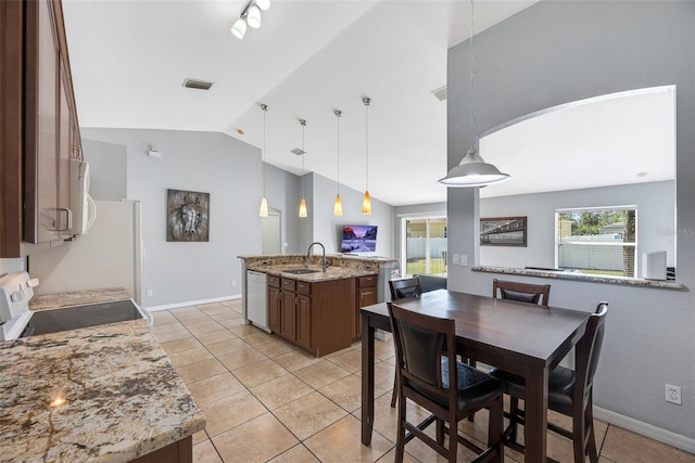 kitchen with pendant lighting, sink, white appliances, light stone counters, and a center island with sink