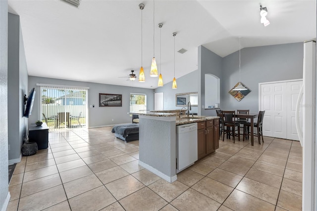 kitchen with sink, white appliances, hanging light fixtures, light stone counters, and light tile patterned flooring