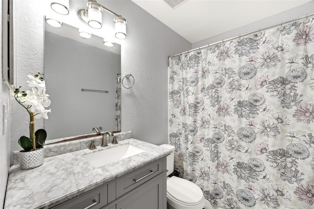 bathroom featuring vanity, walk in shower, and toilet