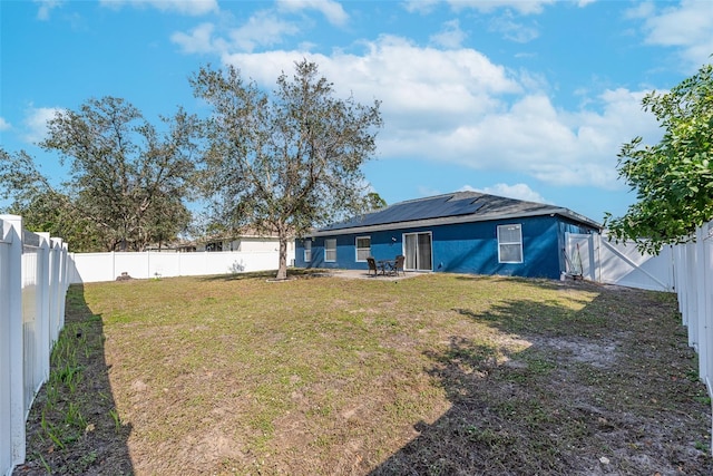 rear view of house featuring a lawn and solar panels