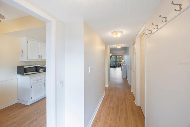 hallway featuring light hardwood / wood-style flooring and a textured ceiling