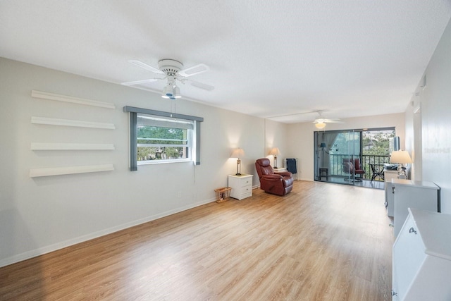 living area with a textured ceiling, plenty of natural light, light hardwood / wood-style floors, and ceiling fan