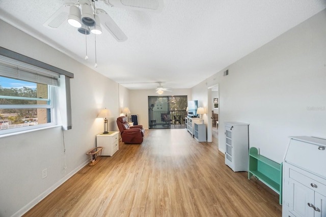 sitting room with ceiling fan, light hardwood / wood-style flooring, and a textured ceiling