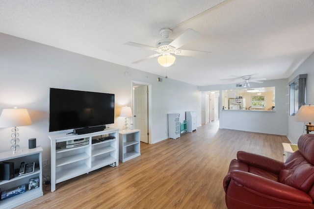 living room with a textured ceiling, ceiling fan, and light hardwood / wood-style flooring