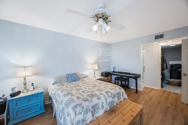 bedroom with dark hardwood / wood-style flooring, a textured ceiling, and ceiling fan