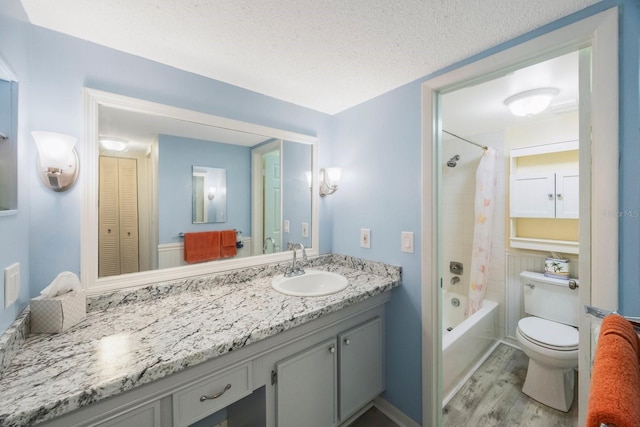 full bathroom with shower / bath combo, vanity, wood-type flooring, a textured ceiling, and toilet