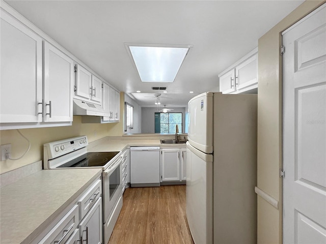 11485 Oakhurst Rd Unit A301, Largo, FL 33774 - kitchen featuring white appliances, under cabinet range hood, wood finished floors, light countertops, and white cabinetry