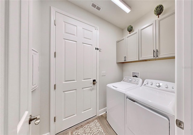 laundry room with cabinets, light hardwood / wood-style floors, and washer and dryer