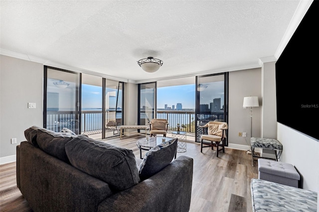 living room featuring a water view, crown molding, a textured ceiling, hardwood / wood-style flooring, and expansive windows