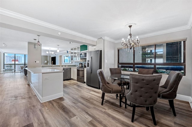 dining room with an inviting chandelier, ornamental molding, and light wood-type flooring