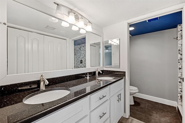 bathroom with tile patterned flooring, vanity, a textured ceiling, and toilet