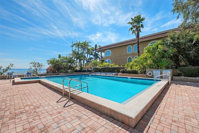 view of swimming pool featuring a water view and a patio