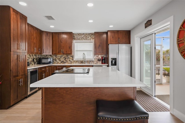 kitchen with a kitchen island, tasteful backsplash, beverage cooler, a kitchen bar, and stainless steel fridge with ice dispenser