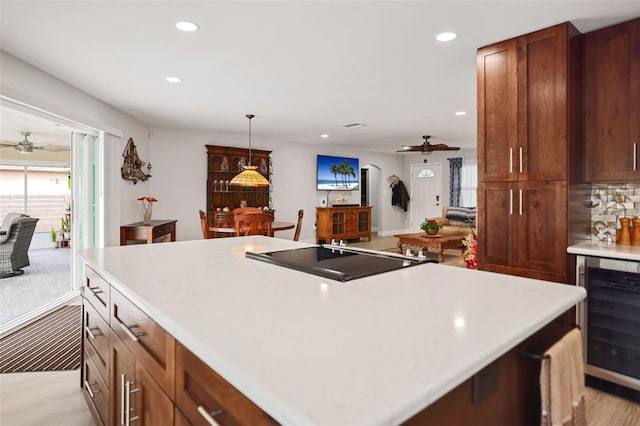 kitchen featuring ceiling fan, beverage cooler, black electric cooktop, and decorative light fixtures