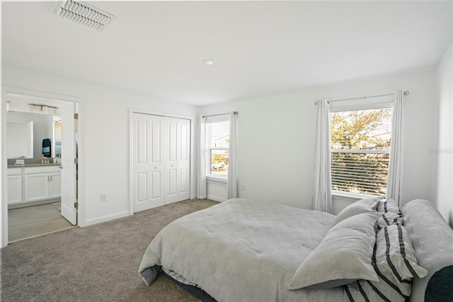 bedroom featuring ensuite bath, a closet, and light carpet