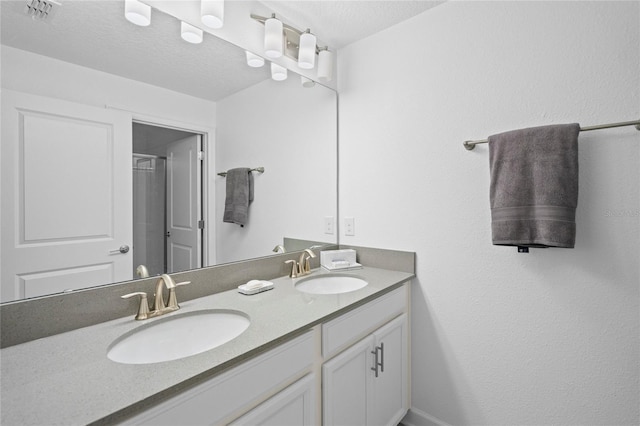 bathroom featuring vanity, a shower with door, and a textured ceiling